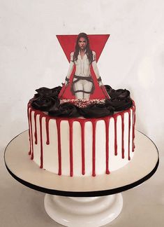 a white cake with red and black icing on it, featuring a woman holding a knife