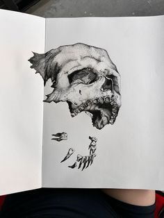 a person holding an open book with a drawing of a human skull in the middle