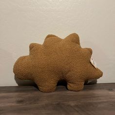 a brown stuffed animal sitting on top of a wooden floor next to a white wall