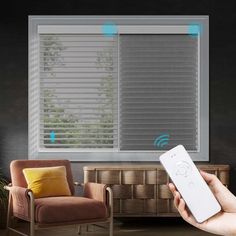 a hand holding a remote control in front of a window with blind shades on it