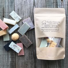 several different types of soaps on top of a wooden table next to a bag