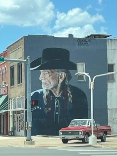 an old man wearing a cowboy hat is painted on the side of a large building