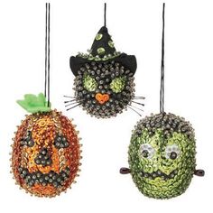 three ornaments are hanging from the ceiling in different styles and colors, each decorated like a pumpkin