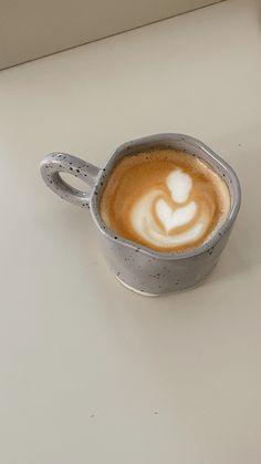 a cappuccino with a heart drawn in it on a white counter top