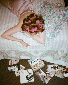 a woman laying on top of a bed with lots of hair clips in her hair