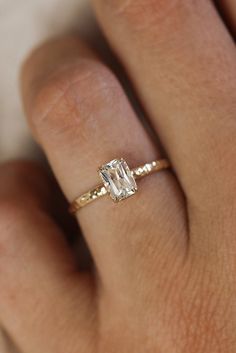 a woman's hand with a diamond ring on top of her finger and an engagement band