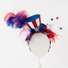 a patriotic hat with red, white and blue feathers on the top is shown against a white background