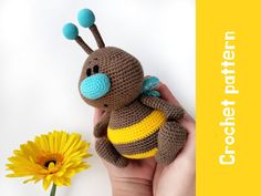 a crocheted stuffed animal sitting next to a yellow flower