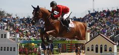 a man riding on the back of a brown horse in front of a large crowd