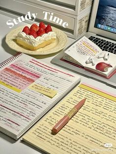 a laptop computer sitting on top of a desk next to an open notebook and strawberry pie