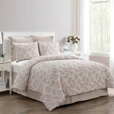 a bed with a white headboard and beige comforter in front of a window