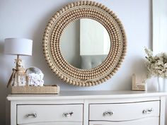 a white dresser with a round mirror above it