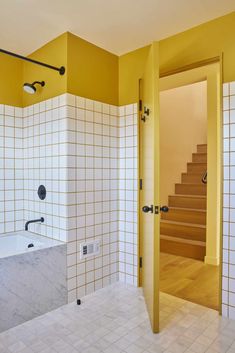 a bathroom with yellow walls and white tiles on the wall, along with a bathtub