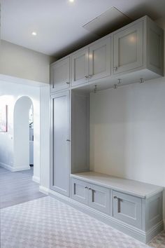 an empty room with white cabinets and gray cupboards on the wall, in front of a doorway