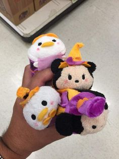 a hand holding three small stuffed animals in it's palm, with one penguin on the other