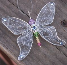 a glass flower ornament hanging from a wooden table with beads and crystals on it