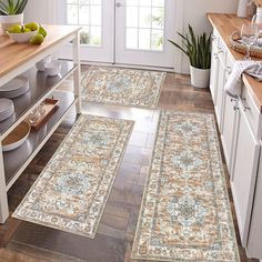 three rugs in the middle of a kitchen with fruit on the counter and plates