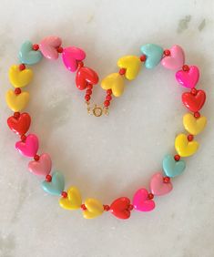 "Kids Brite Multi Colored Plastic Heart Necklace with Red Mini Spacer Beads Gold Tone Spring Ring Clasp Closure Brite Multi Hearts are Red, Hot Pink, Pink, Aqua, Yellow Hearts Measure 5/8\" Wide Necklace Measures 15\" Imported COMPLIMENTARY DOMESTIC SHIPPING" Red Beaded Necklace For Valentine's Day Gift, Red Round Beaded Necklaces For Valentine's Day, Red Round Beads Necklace For Valentine's Day, Playful Heart Beads For Jewelry Making, Cute Multicolor Jewelry With Heart Beads, Valentine's Day Red Beaded Necklaces, Cute Multicolor Heart Beads Jewelry, Valentine's Day Heart Charm Necklace With Round Beads, Valentine's Day Necklace With Heart Charm And Round Beads