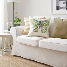 a living room filled with furniture and pillows on top of a white couch next to a window