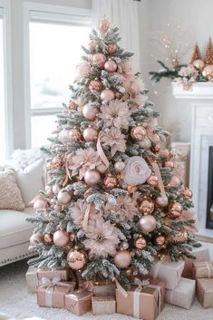 a decorated christmas tree with pink and gold ornaments in a white living room, surrounded by presents