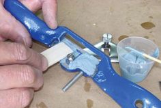 a man is working on something with blue paint and pliers next to it are tools