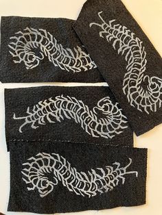 three pieces of black fabric with white embroidery on them, one has a dragon design