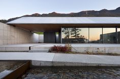 the building has large windows and is surrounded by stone steps, with mountains in the background