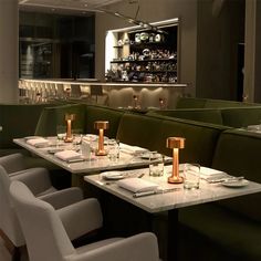 an empty restaurant with green booths and white tablecloths, gold candle holders on the tables