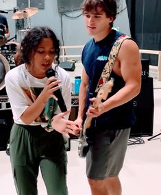 a boy and girl standing next to each other in front of musical equipment on stage