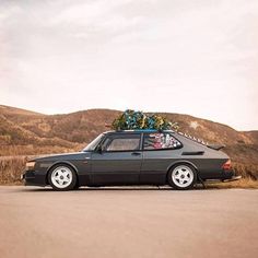 a black car parked on the side of a road with luggage strapped to it's roof