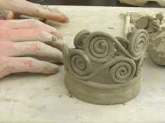 two hands are working on a clay sculpture