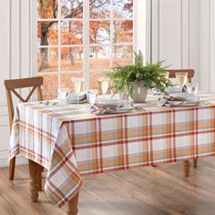 the table is set with dishes and cups on it, next to an open window