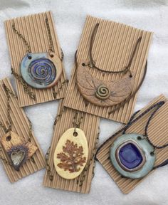 four necklaces with different designs on them sitting on top of a sheet of paper