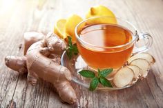 a glass cup filled with tea next to sliced lemons and ginger