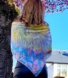 a woman standing next to a tree wearing a colorful shawl over her shoulders and back