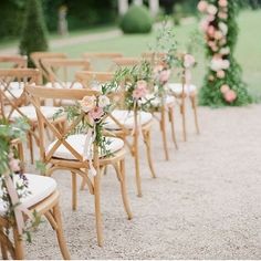 the chairs are lined up with flowers and greenery at the end of the aisle