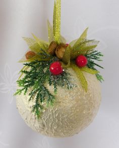 a white ornament with green and red decorations on it's side hanging from a string