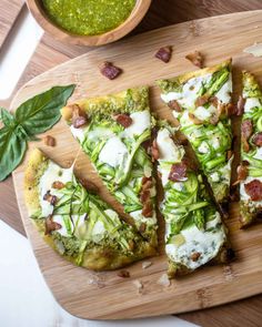 slices of pizza on a cutting board with pesto sauce