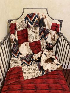 a red and white blanket sitting on top of a crib next to a pillow