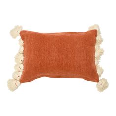 an orange and white pillow with pom poms on the bottom, sitting against a white background