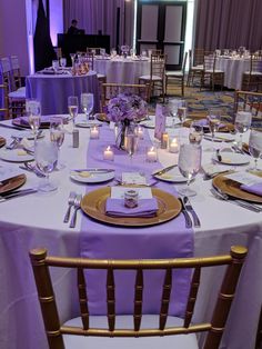 the table is set with purple linens and place settings