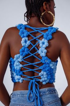 the back of a woman's top with blue crocheted flowers on it