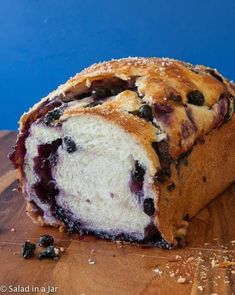 a loaf of blueberry bread sitting on top of a wooden cutting board