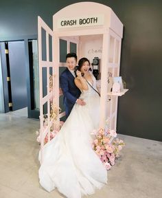 a newly married couple posing in front of a pink booth