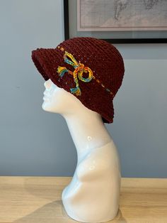 a white mannequin head wearing a brown knitted hat with flowers on it