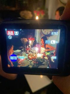 a person holding up a cell phone to take a photo with candles on the table