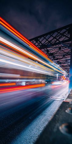 blurry photograph of city street at night with bridge in the backgrouund