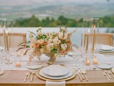 the table is set with white and gold plates, silverware, and floral centerpieces