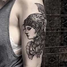 a woman's arm with a black and white tattoo design on the left shoulder