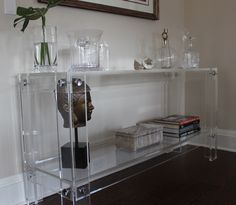 a clear shelf with vases and other items on it in a living room area